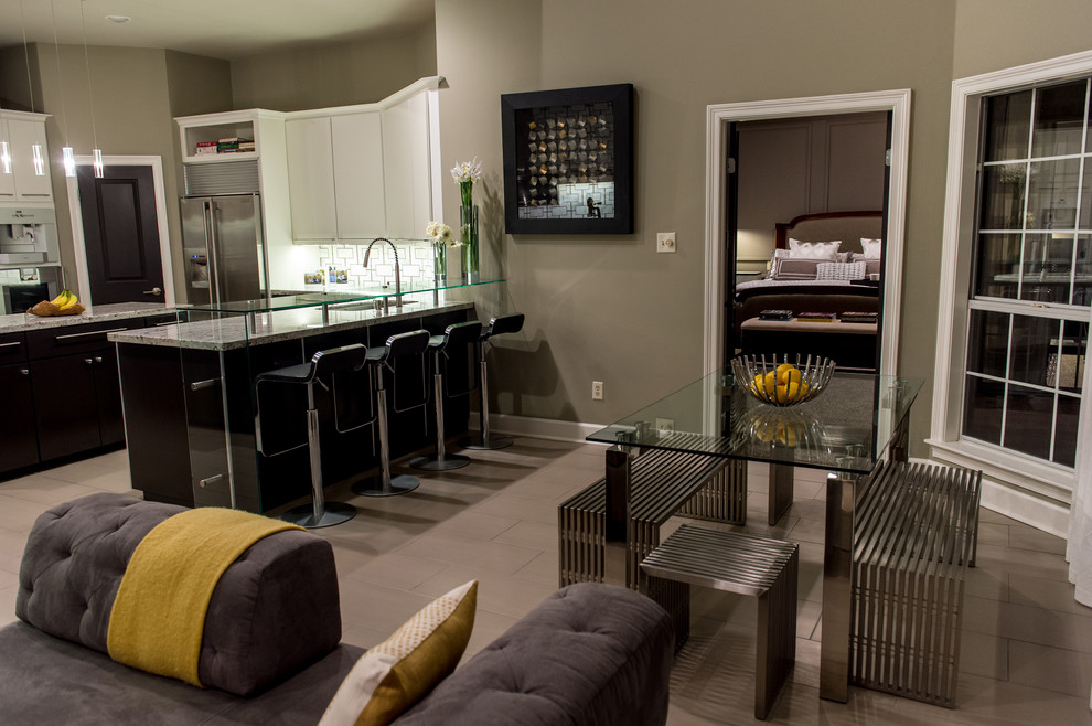 Photo of a mid-sized contemporary u-shaped eat-in kitchen in New Orleans with an integrated sink, flat-panel cabinets, black cabinets, granite benchtops, multi-coloured splashback, stainless steel appliances, limestone floors and with island.