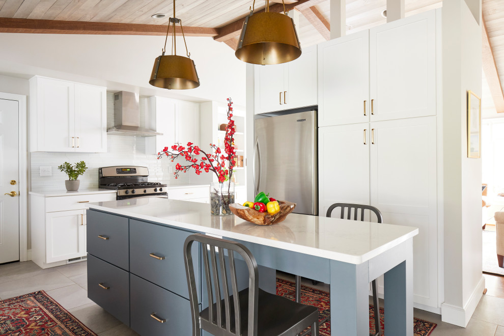 Mid-sized transitional u-shaped ceramic tile, gray floor and vaulted ceiling eat-in kitchen photo with an undermount sink, shaker cabinets, white cabinets, quartz countertops, white backsplash, glass tile backsplash, stainless steel appliances, an island and white countertops