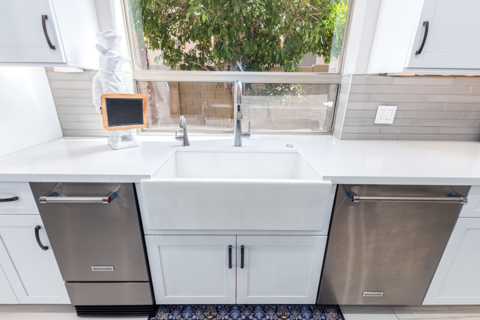 Transitional kitchen photo in Phoenix with a farmhouse sink, shaker cabinets, white cabinets, gray backsplash, stainless steel appliances and white countertops