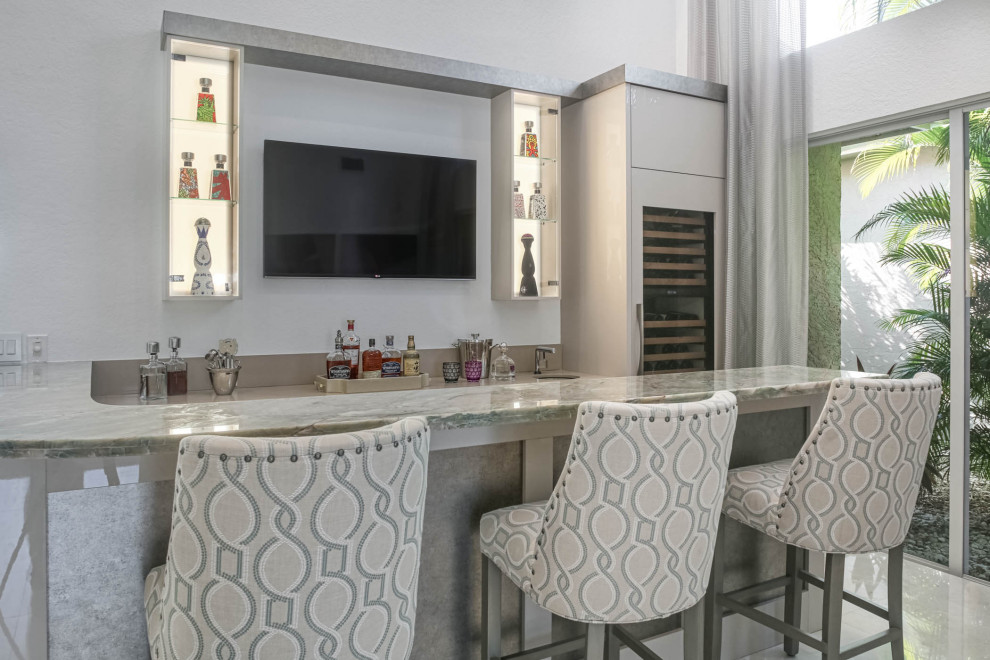 Photo of a small modern single-wall seated home bar in Miami with a drop-in sink, open cabinets, beige cabinets, quartzite benchtops and beige benchtop.