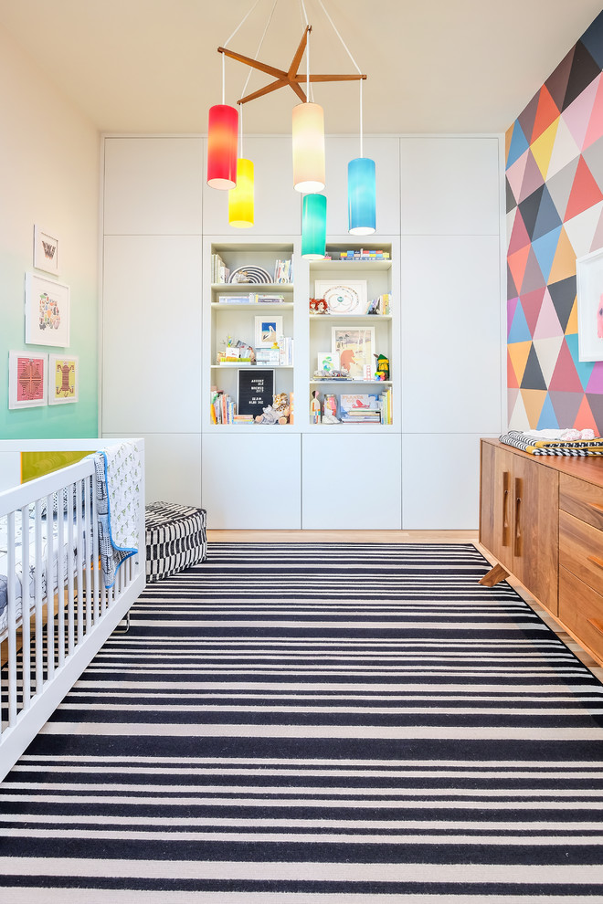 Contemporary gender-neutral nursery in San Francisco with multi-coloured walls, light hardwood floors and beige floor.