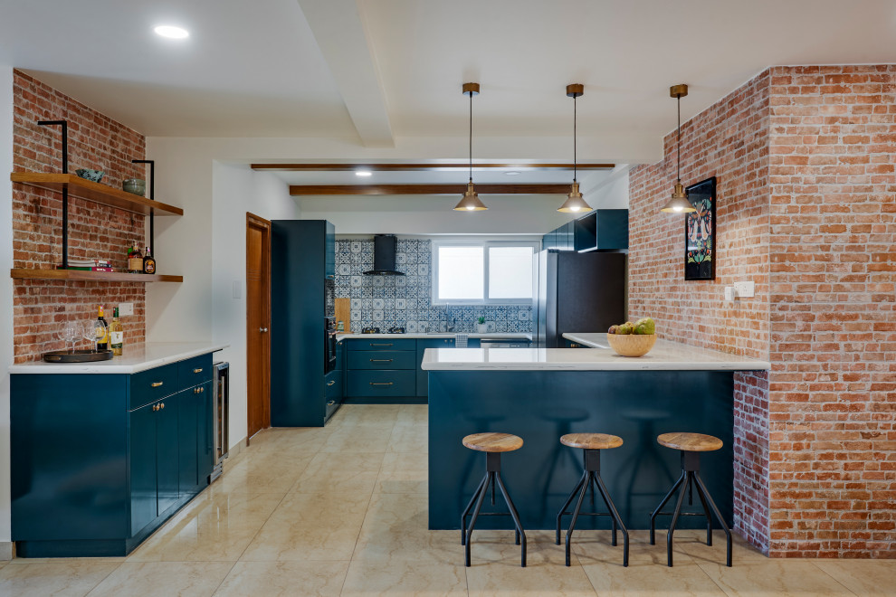 Photo of an industrial u-shaped kitchen in Bengaluru with flat-panel cabinets, blue cabinets, blue splashback, black appliances, a peninsula, beige floor and white benchtop.