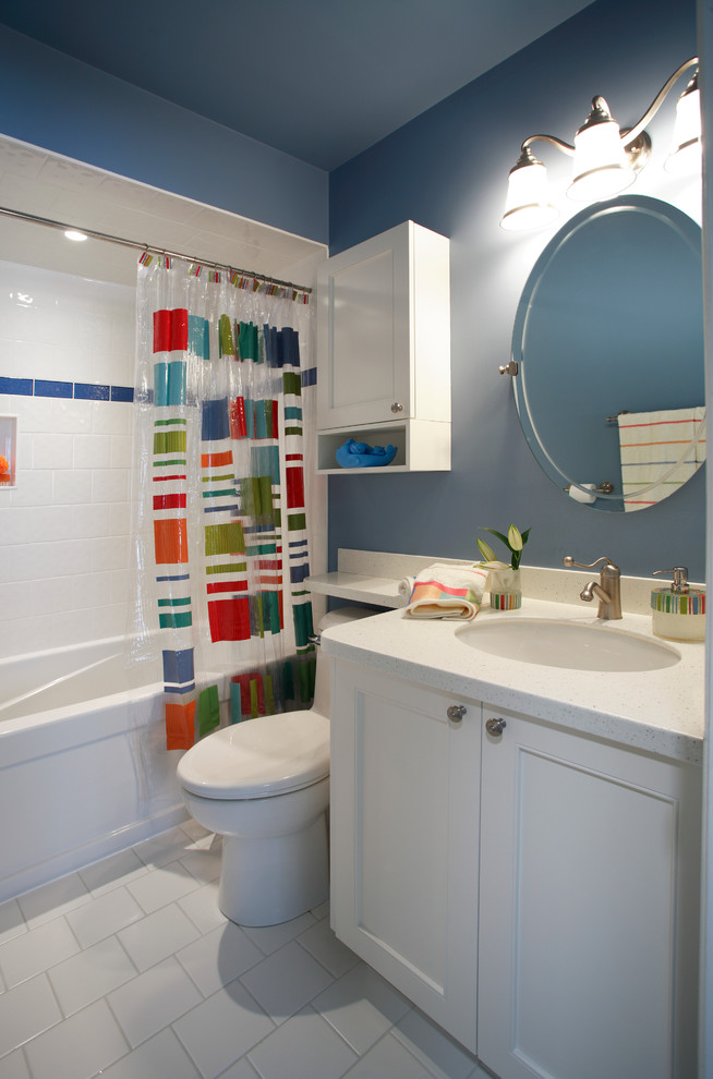 This is an example of a small traditional kids bathroom in Toronto with an undermount sink, shaker cabinets, white cabinets, solid surface benchtops, an alcove tub, a shower/bathtub combo, a one-piece toilet, white tile, porcelain tile, blue walls and porcelain floors.