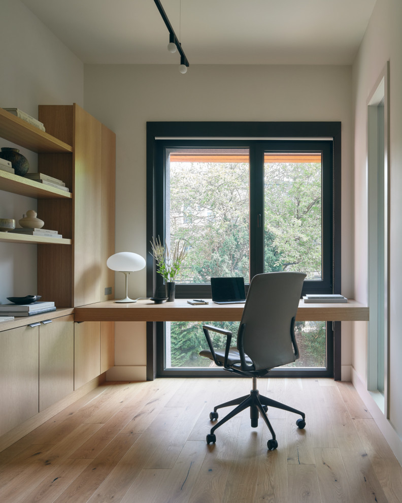 Example of a trendy built-in desk light wood floor and beige floor home office design in New York with white walls
