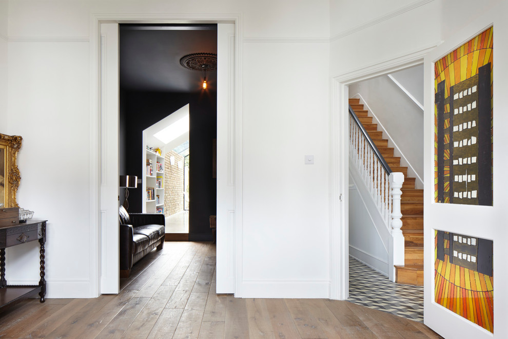 Small traditional foyer in London with white walls, dark hardwood floors and a single front door.
