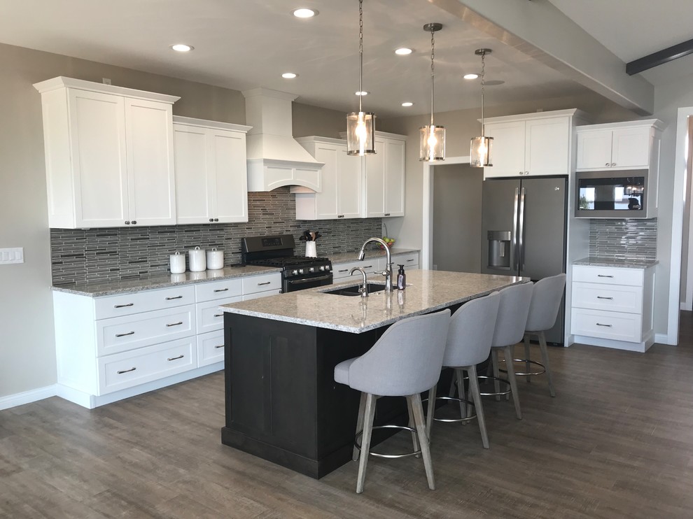 Inspiration for a large transitional l-shaped open concept kitchen remodel in Cedar Rapids with an undermount sink, white cabinets, quartz countertops, gray backsplash, glass tile backsplash, stainless steel appliances, an island, gray countertops and shaker cabinets