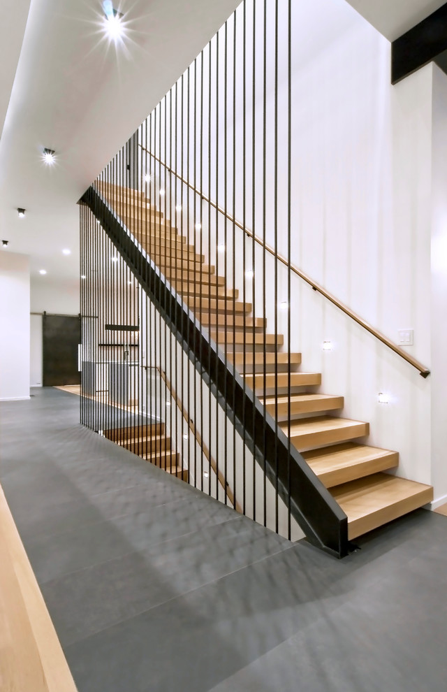 This is an example of a mid-sized industrial wood straight staircase in Chicago with open risers and metal railing.