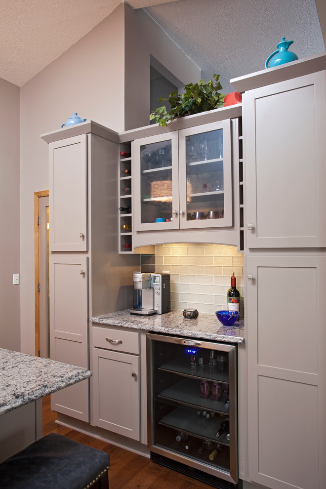 Inspiration for a mid-sized transitional l-shaped medium tone wood floor enclosed kitchen remodel in Minneapolis with an undermount sink, recessed-panel cabinets, gray cabinets, quartz countertops, green backsplash, glass tile backsplash, stainless steel appliances, gray walls and an island