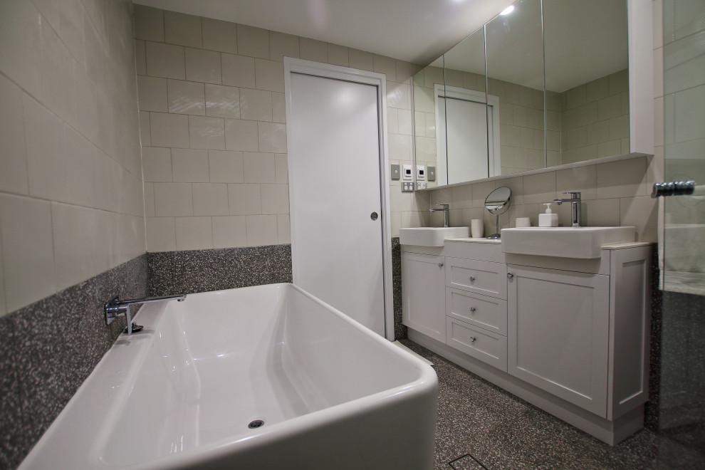 Design ideas for a mid-sized transitional bathroom in Sydney with shaker cabinets, white cabinets, a corner tub, an open shower, a one-piece toilet, white tile, porcelain tile, multi-coloured walls, terrazzo floors, a drop-in sink, tile benchtops, multi-coloured floor, a hinged shower door, white benchtops, a double vanity and a freestanding vanity.