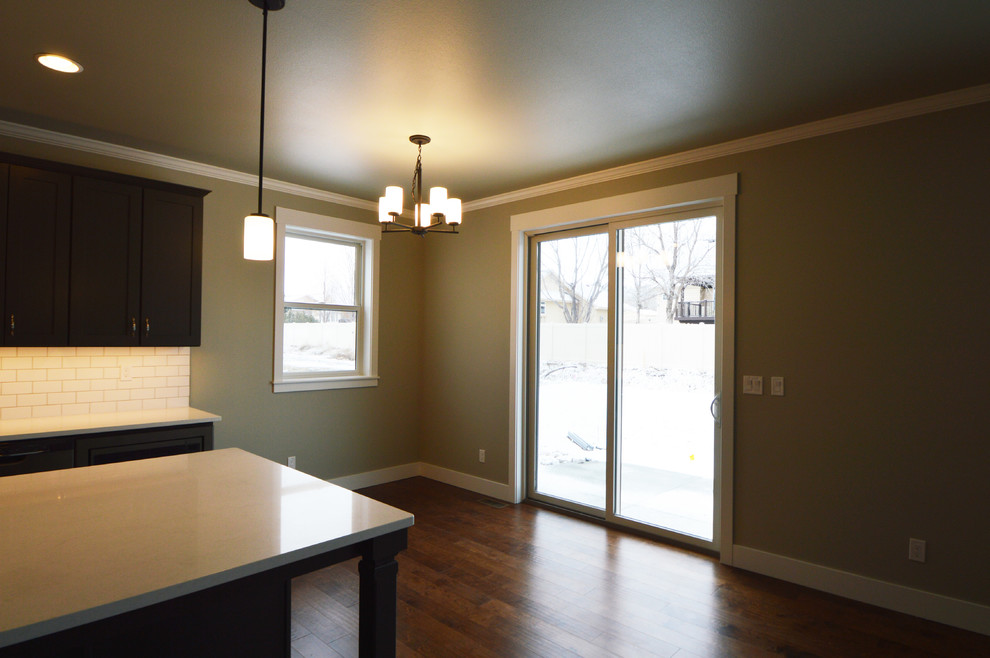 Example of a mid-sized transitional l-shaped dark wood floor open concept kitchen design with an undermount sink, shaker cabinets, brown cabinets, quartzite countertops, white backsplash, subway tile backsplash and an island