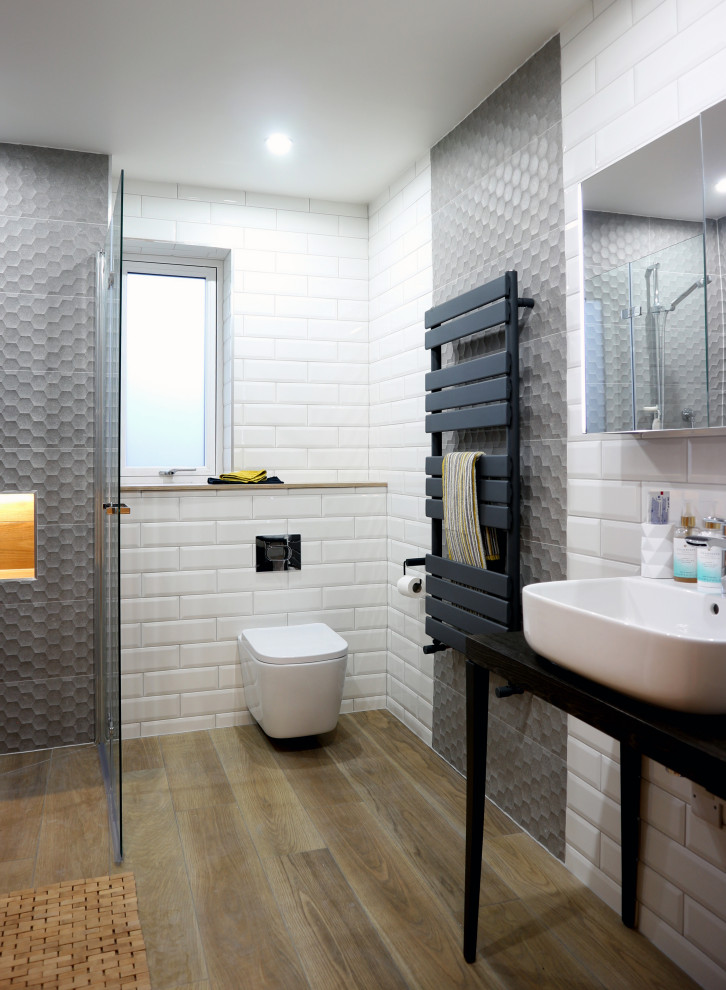 Large modern master wet room bathroom in Hertfordshire with dark wood cabinets, a wall-mount toilet, white tile, subway tile, grey walls, ceramic floors, a console sink, brown floor, a single vanity, a freestanding vanity and an open shower.