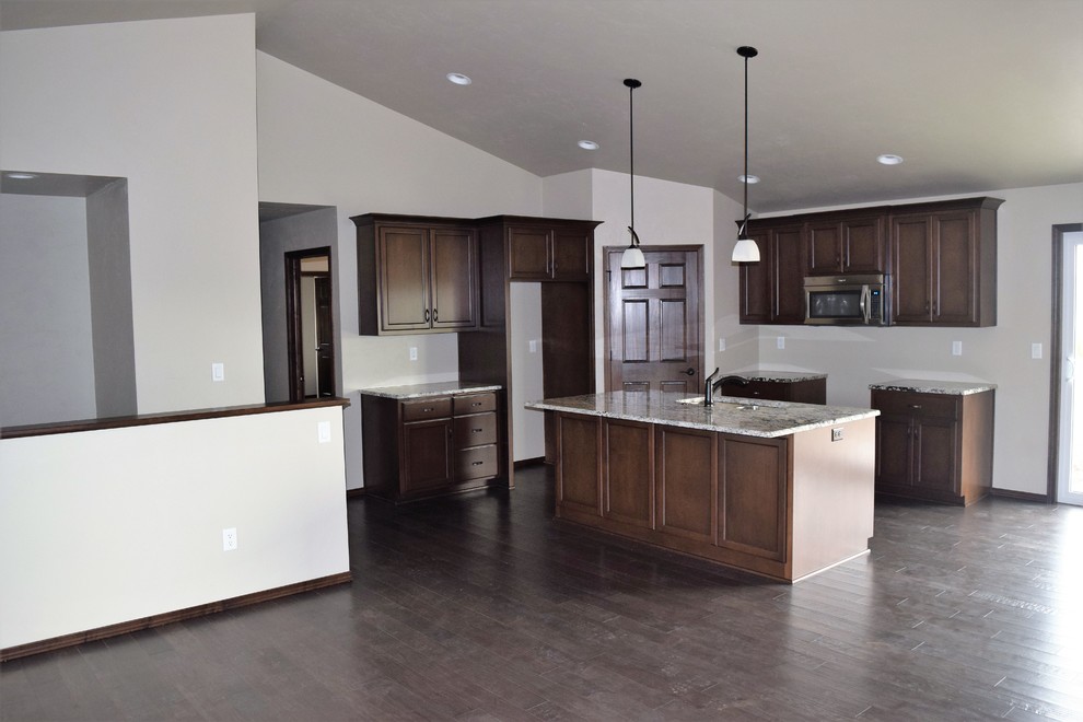 Example of a mountain style kitchen design with white cabinets, stainless steel appliances and an island