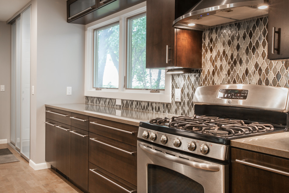Example of a transitional galley cork floor and gray floor eat-in kitchen design with an undermount sink, flat-panel cabinets, dark wood cabinets, quartz countertops, mosaic tile backsplash, stainless steel appliances and a peninsula
