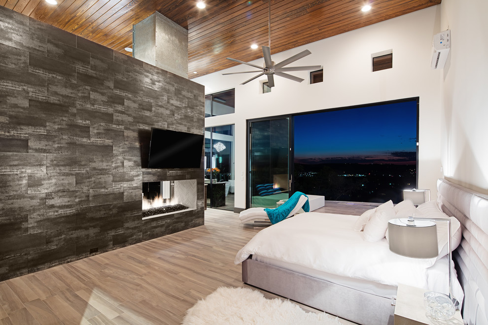 Inspiration for a large modern master bedroom in Austin with white walls, porcelain floors, a two-sided fireplace and a tile fireplace surround.