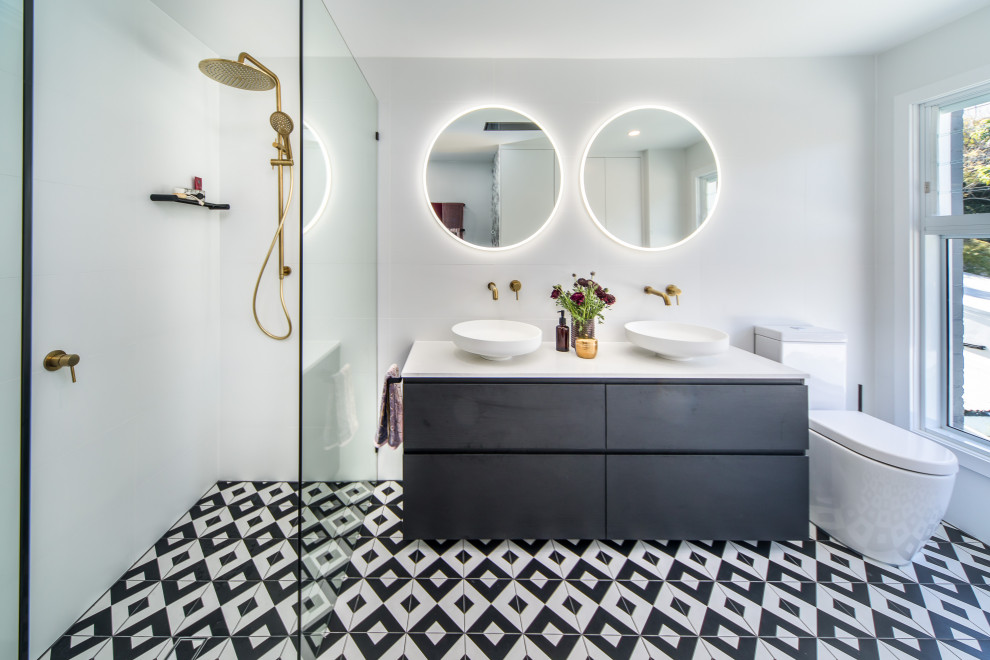 Photo of a contemporary master bathroom in Sydney with a one-piece toilet, white tile, ceramic tile, white walls, cement tiles, an open shower, white benchtops, flat-panel cabinets, black cabinets, a curbless shower, a vessel sink and multi-coloured floor.