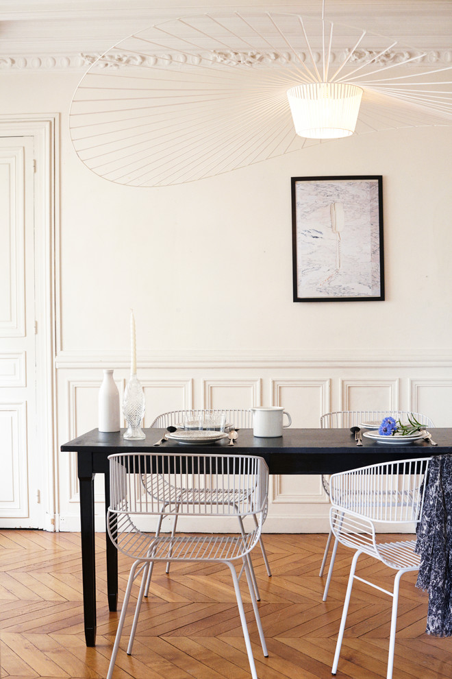 This is an example of a mid-sized contemporary open plan dining in Paris with white walls and medium hardwood floors.