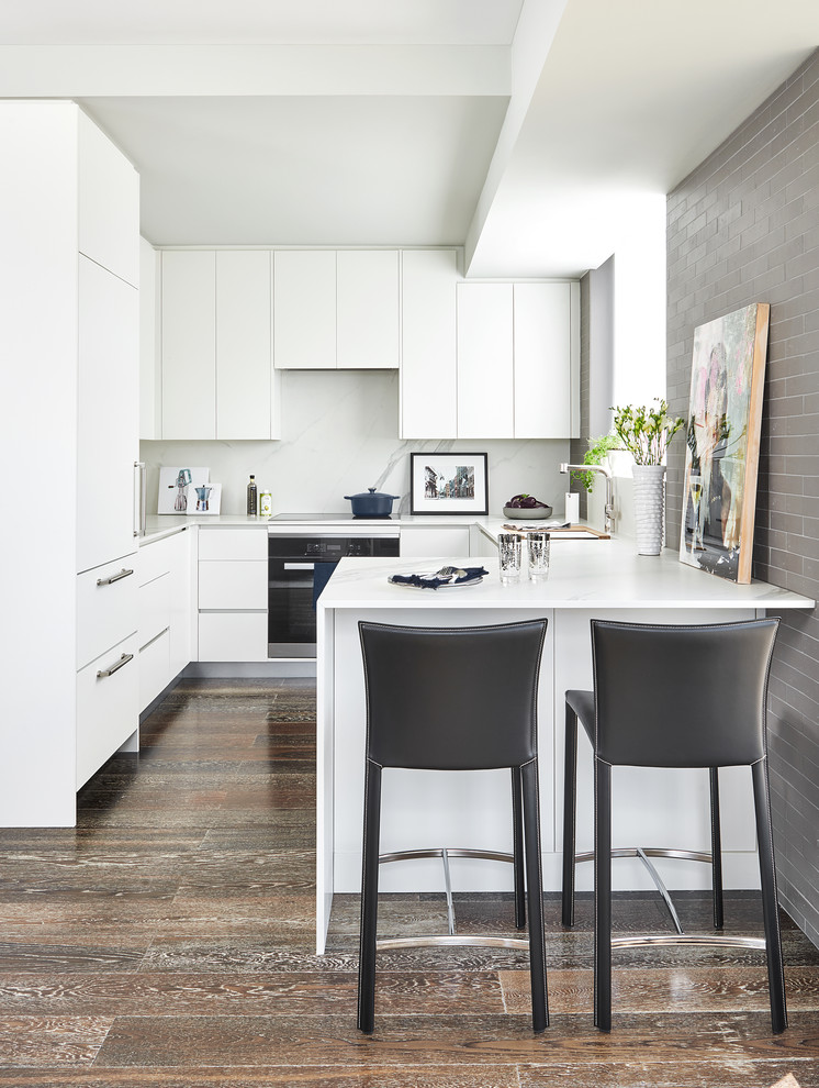 Design ideas for a small contemporary u-shaped separate kitchen in Toronto with an undermount sink, flat-panel cabinets, white cabinets, quartz benchtops, white splashback, marble splashback, dark hardwood floors, a peninsula, brown floor, white benchtop and stainless steel appliances.