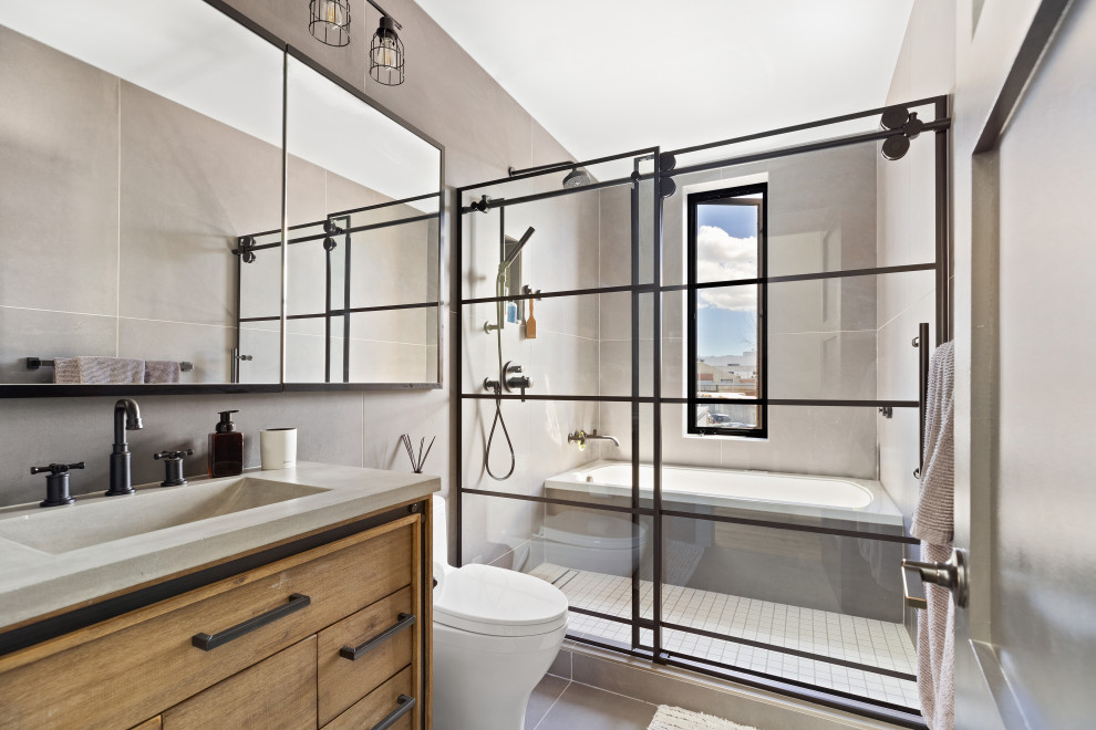 Пример оригинального дизайна: маленькая главная ванная комната в стиле модернизм с фасадами островного типа, коричневыми фасадами, угловой ванной, душевой комнатой, унитазом-моноблоком, серой плиткой, керамической плиткой, серыми стенами, полом из керамической плитки, монолитной раковиной, столешницей из бетона, серым полом, душем с раздвижными дверями, серой столешницей, тумбой под одну раковину и напольной тумбой для на участке и в саду