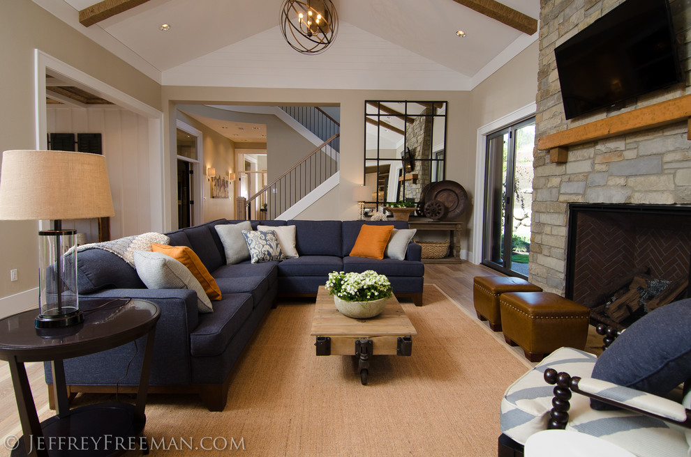 This is an example of a large contemporary open concept living room in Portland with beige walls, light hardwood floors, a standard fireplace, a stone fireplace surround and a wall-mounted tv.