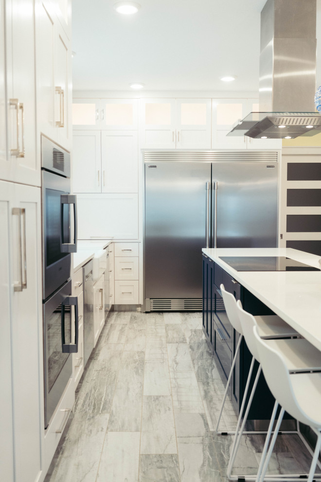 Design ideas for a large modern u-shaped kitchen pantry in Other with a farmhouse sink, shaker cabinets, yellow cabinets, quartz benchtops, blue splashback, glass tile splashback, stainless steel appliances, porcelain floors, with island, grey floor and white benchtop.