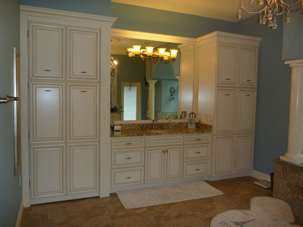 Expansive mediterranean master bathroom in Tampa with raised-panel cabinets, white cabinets, a drop-in tub, beige tile, ceramic tile, blue walls, ceramic floors, an undermount sink, granite benchtops and beige floor.