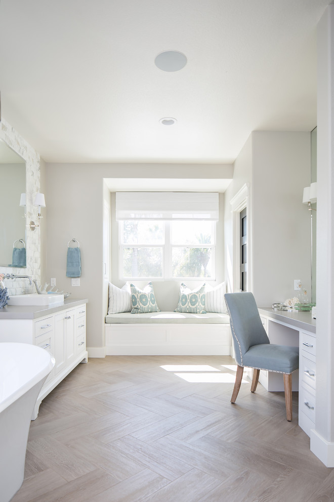 Large beach style master bathroom in San Diego with a freestanding tub, grey walls, light hardwood floors, engineered quartz benchtops, white cabinets, a vessel sink, beige floor, grey benchtops and recessed-panel cabinets.