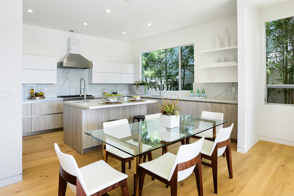 This is an example of a contemporary kitchen/dining combo in Los Angeles with white walls and light hardwood floors.