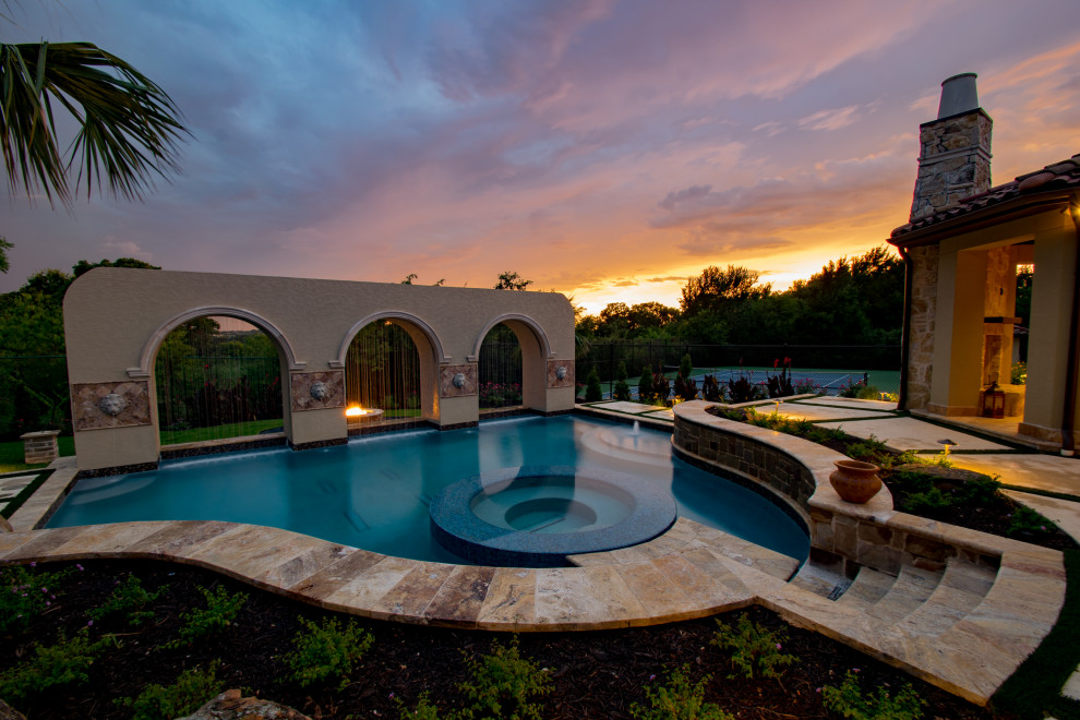 Large modern backyard custom-shaped infinity pool in Dallas with a water slide and natural stone pavers.