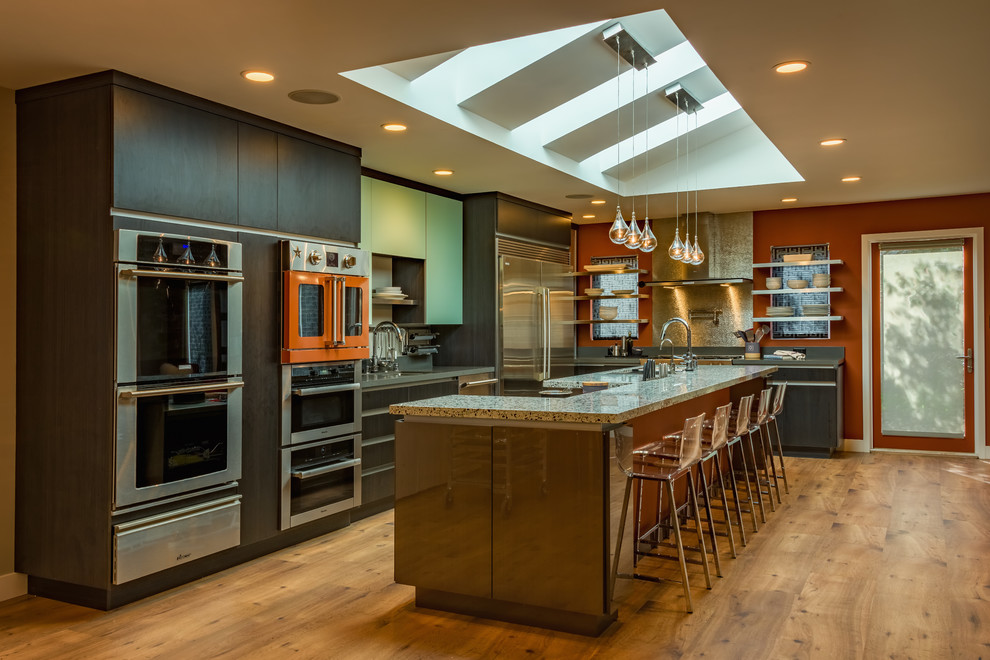 Inspiration for a large contemporary l-shaped open plan kitchen in San Francisco with an undermount sink, flat-panel cabinets, grey cabinets, recycled glass benchtops, coloured appliances, with island and medium hardwood floors.