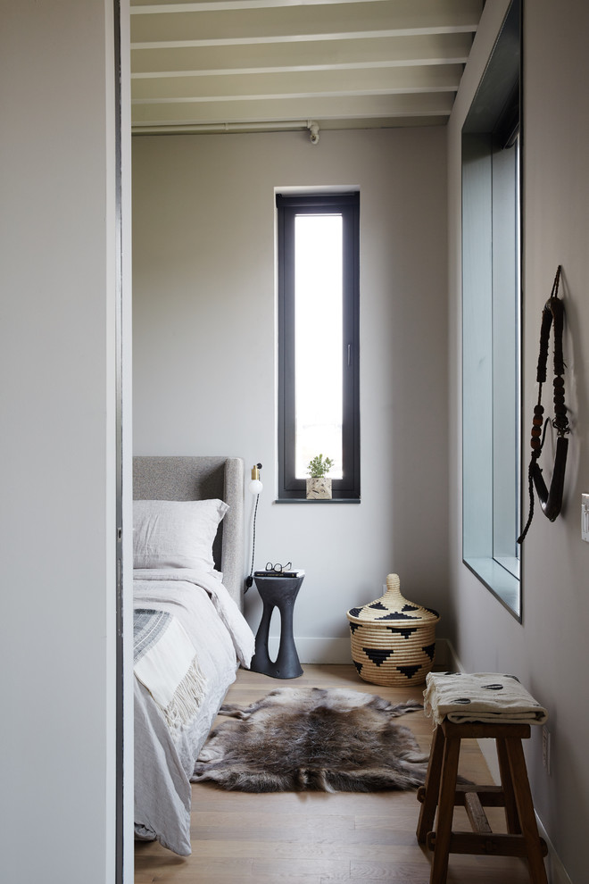 Design ideas for a scandinavian bedroom in New York with grey walls and light hardwood floors.
