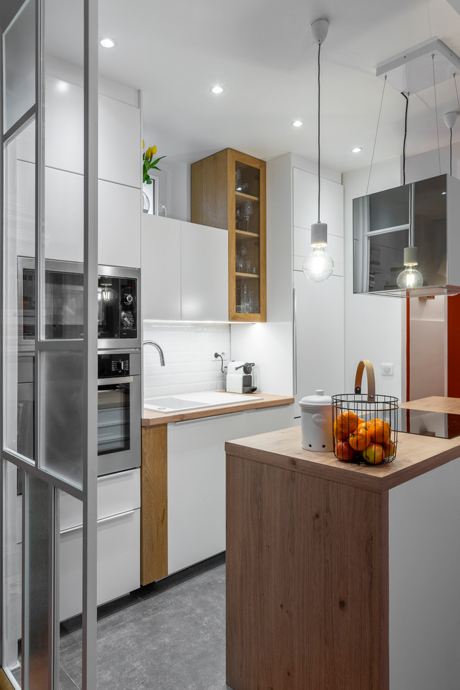 Design ideas for a small modern galley open plan kitchen in Paris with a single-bowl sink, white cabinets, soapstone benchtops, white splashback, subway tile splashback, panelled appliances, ceramic floors, with island, grey floor and brown benchtop.