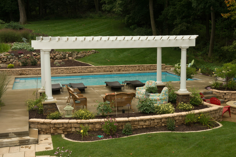 Design ideas for a large midcentury backyard rectangular pool in Cedar Rapids with a water feature and concrete slab.