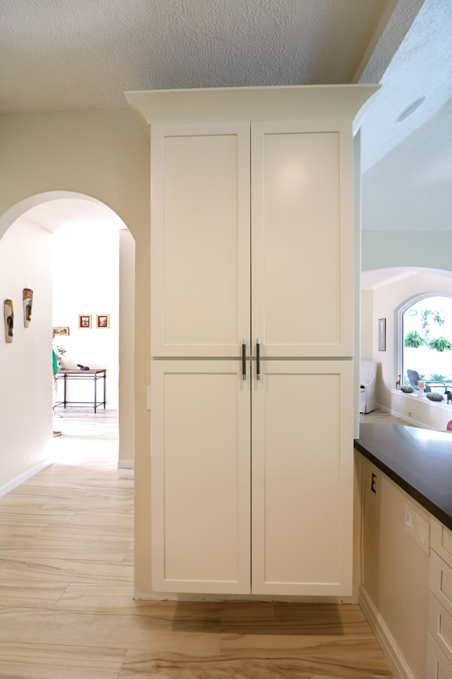 Eat-in kitchen - mid-sized transitional u-shaped porcelain tile and beige floor eat-in kitchen idea in Houston with an undermount sink, recessed-panel cabinets, white cabinets, soapstone countertops, white backsplash, subway tile backsplash, stainless steel appliances, an island and black countertops