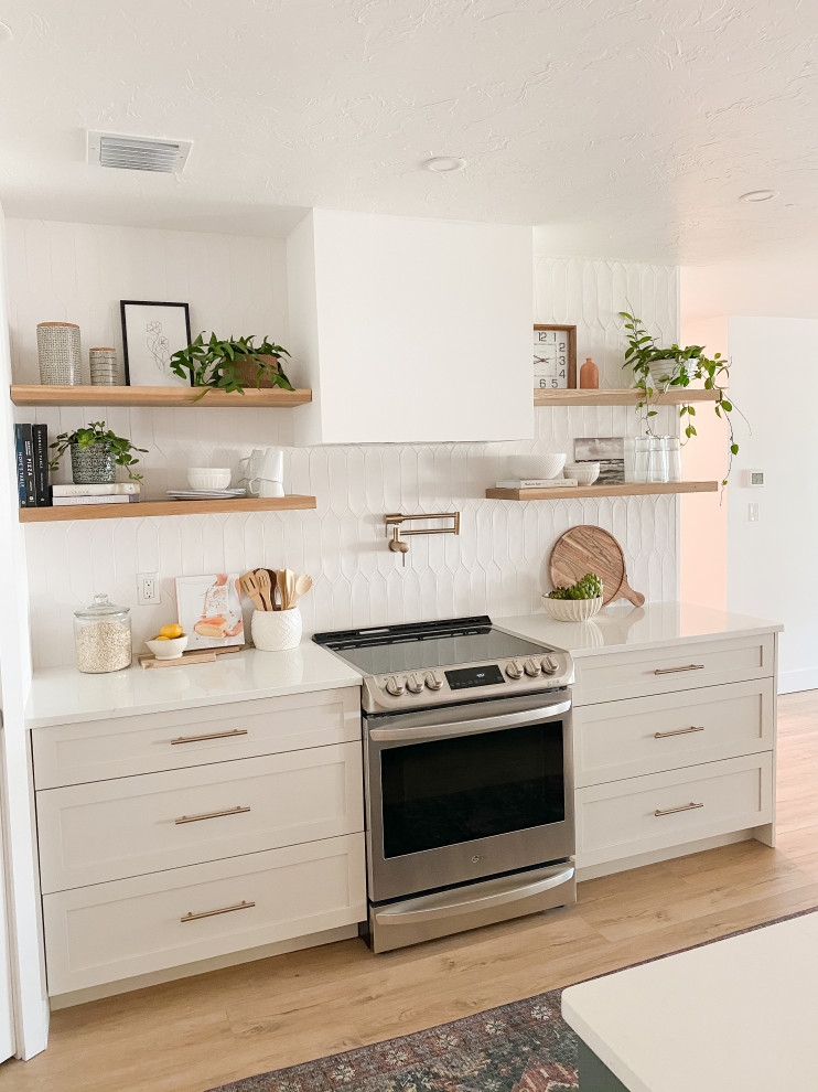 Foto på ett mellanstort funkis vit kök, med skåp i shakerstil, beige skåp, bänkskiva i kvartsit, vitt stänkskydd, stänkskydd i keramik, rostfria vitvaror, vinylgolv och en köksö