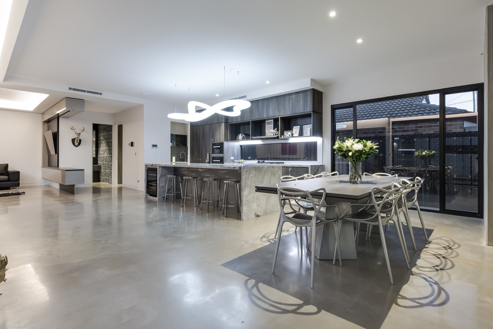 Photo of a mid-sized industrial galley eat-in kitchen in Brisbane with an undermount sink, beaded inset cabinets, medium wood cabinets, marble benchtops, glass sheet splashback, black appliances, concrete floors, with island and beige floor.