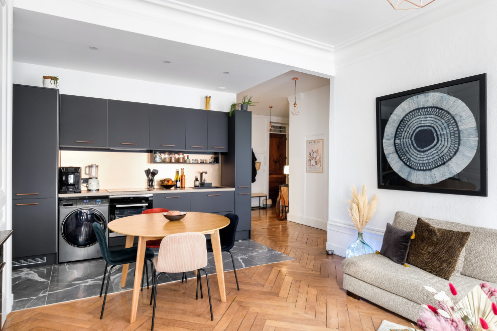 This is an example of a contemporary single-wall open plan kitchen in Bordeaux with flat-panel cabinets, black cabinets, integrated appliances, no island, grey floors and grey worktops.