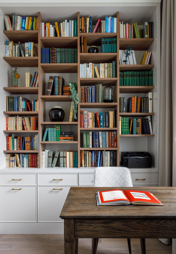 Idee per uno studio classico di medie dimensioni con libreria, pareti bianche, pavimento in legno massello medio, scrivania autoportante e pavimento grigio