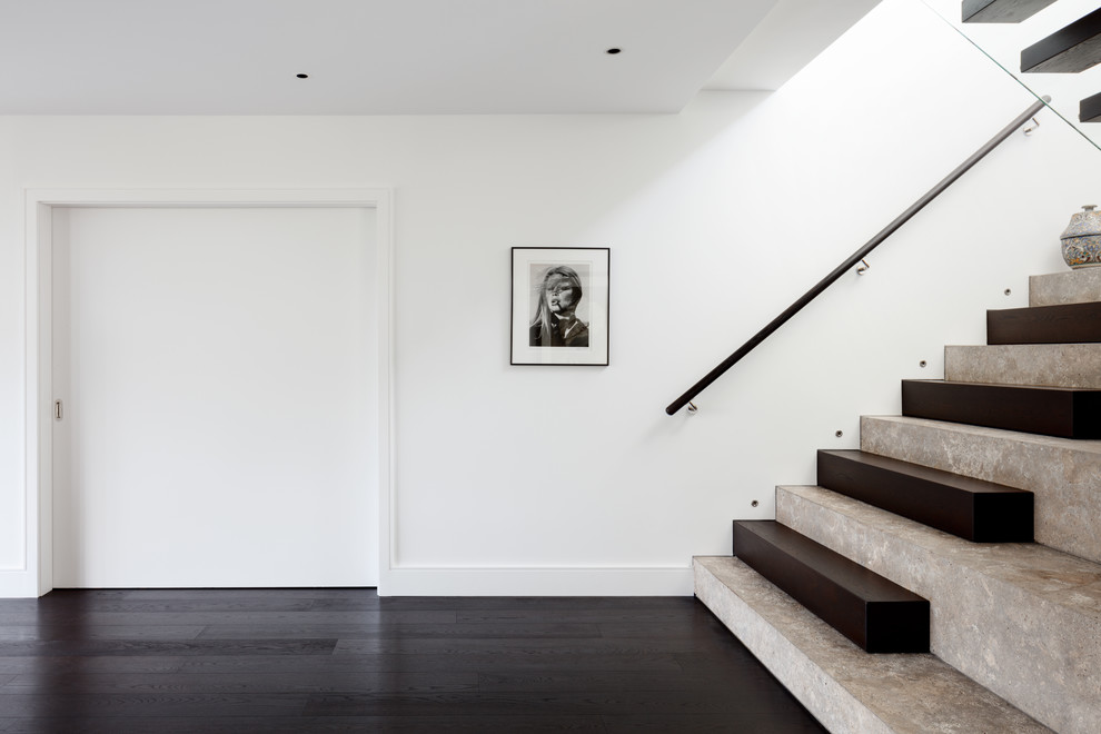 Photo of a large contemporary limestone u-shaped staircase in London with wood risers and wood railing.