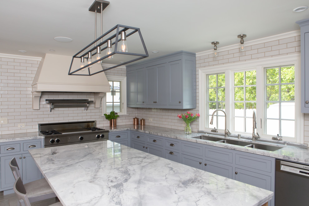 Large transitional u-shaped porcelain tile and gray floor enclosed kitchen photo in Los Angeles with a drop-in sink, shaker cabinets, quartzite countertops, white backsplash, ceramic backsplash, stainless steel appliances, an island and gray countertops