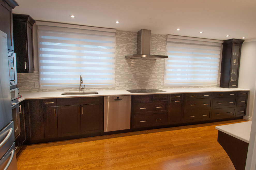 Enclosed kitchen - large transitional galley light wood floor enclosed kitchen idea in Toronto with a single-bowl sink, shaker cabinets, dark wood cabinets, quartzite countertops, beige backsplash, stone tile backsplash, stainless steel appliances and an island