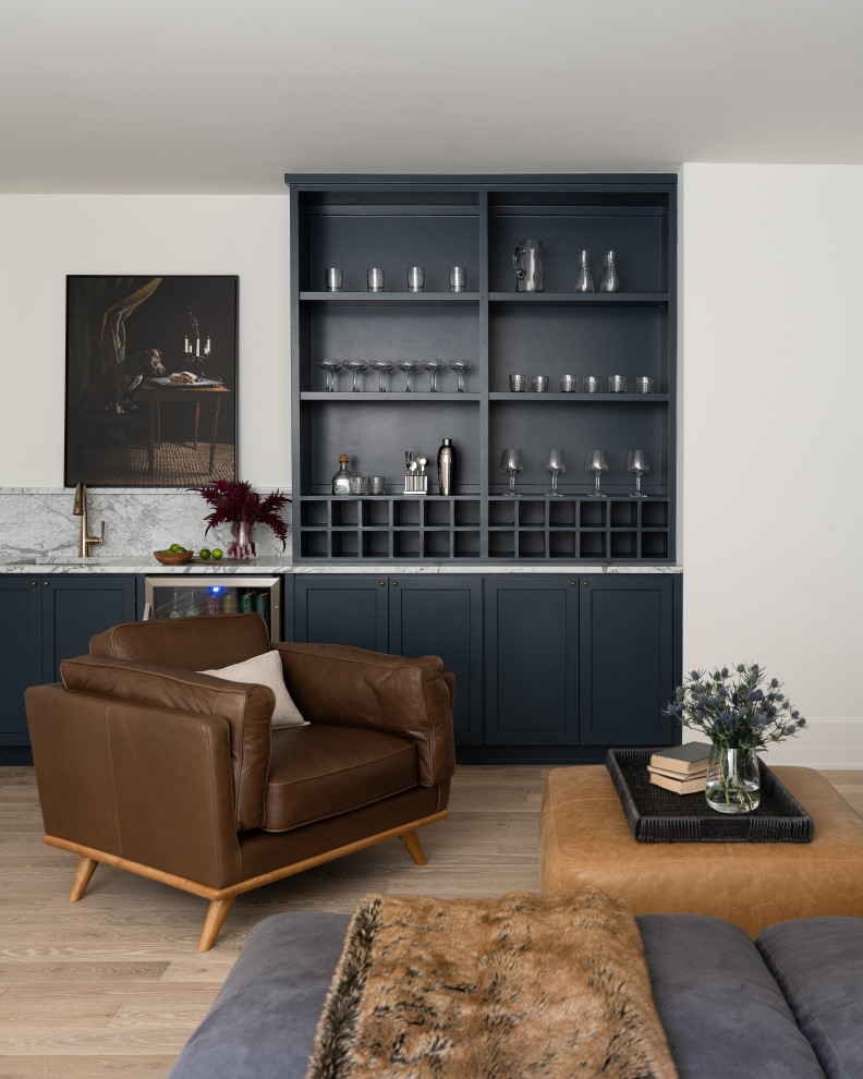 Design ideas for a classic single-wall wet bar in Indianapolis with shaker cabinets, blue cabinets, marble worktops, white splashback, marble splashback, light hardwood flooring, brown floors and white worktops.