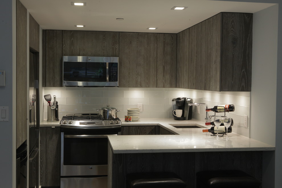 Photo of a mid-sized contemporary u-shaped separate kitchen in New York with an undermount sink, flat-panel cabinets, grey cabinets, terrazzo benchtops, white splashback, glass tile splashback, stainless steel appliances and a peninsula.