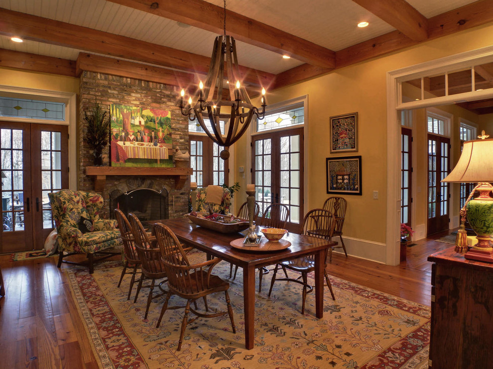 Arts and crafts dining room in Atlanta with yellow walls, medium hardwood floors, a standard fireplace and a brick fireplace surround.