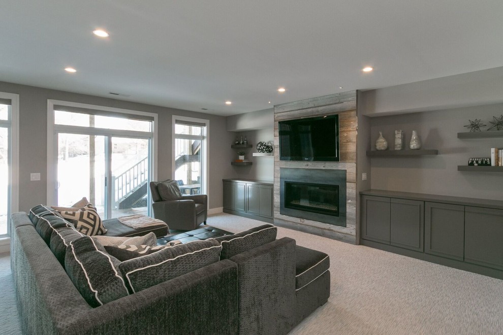 Example of a large transitional walk-out carpeted basement design in Cedar Rapids with gray walls, a standard fireplace and a stone fireplace
