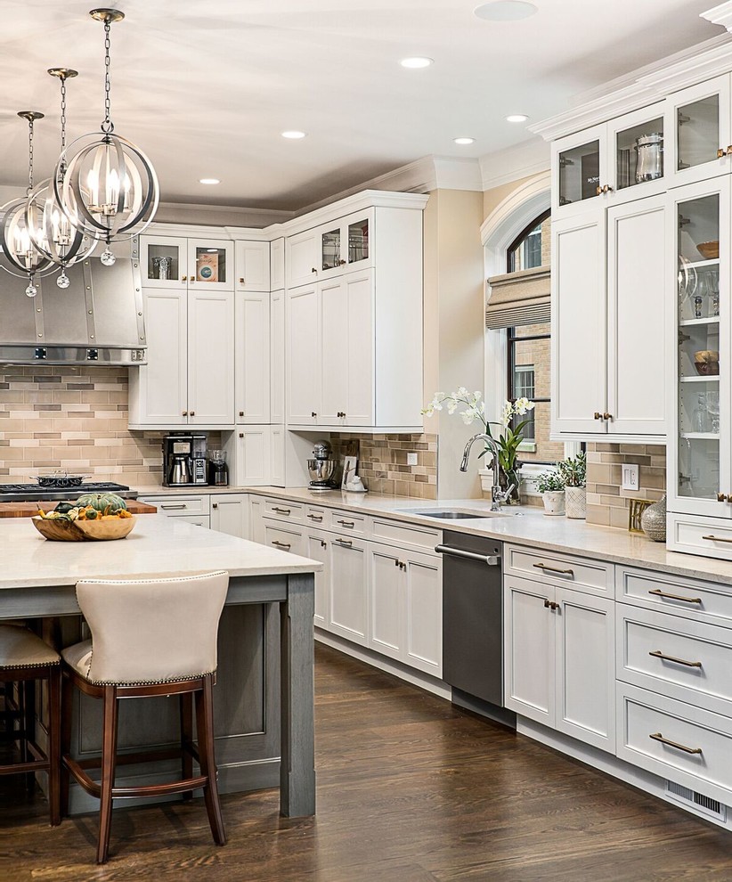 Photo of a large eclectic l-shaped open plan kitchen in Chicago with an undermount sink, shaker cabinets, white cabinets, beige splashback, ceramic splashback, stainless steel appliances, dark hardwood floors, with island, brown floor and beige benchtop.