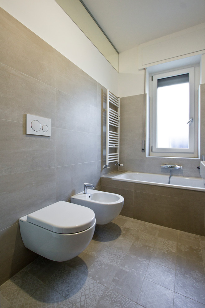 Design ideas for a large contemporary master bathroom in Milan with a drop-in tub, a wall-mount toilet, beige walls, porcelain floors, a wall-mount sink, beige floor, beige tile, porcelain tile and a hinged shower door.