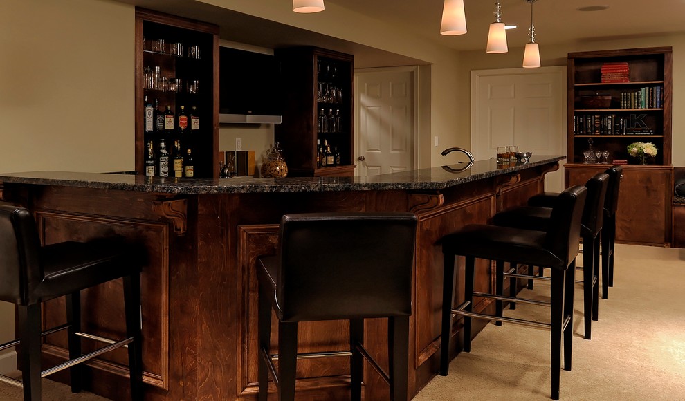 Photo of a large traditional galley seated home bar in DC Metro with an undermount sink, dark wood cabinets, granite benchtops and carpet.