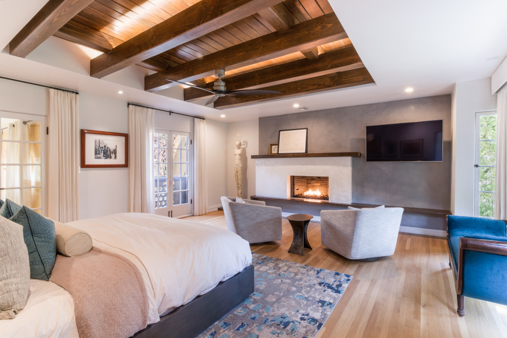 Design ideas for a large transitional master bedroom in Los Angeles with beige walls, medium hardwood floors, a hanging fireplace, a concrete fireplace surround and brown floor.