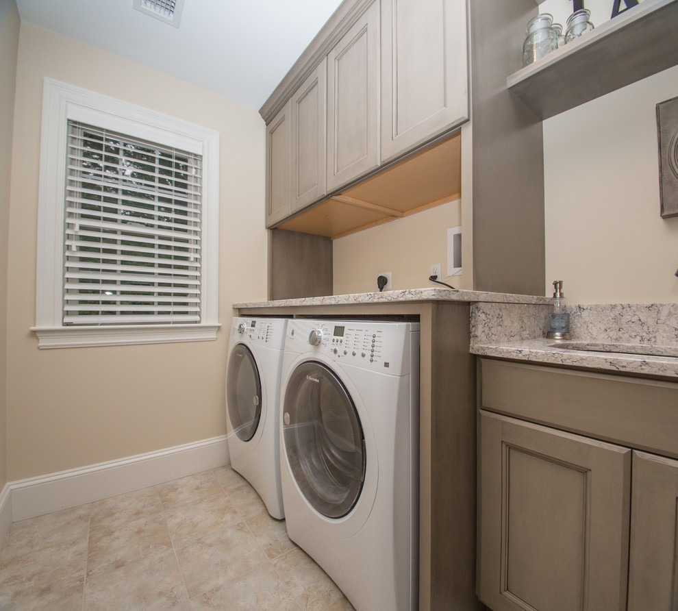 Design ideas for a mid-sized transitional single-wall dedicated laundry room in Boston with an undermount sink, a side-by-side washer and dryer, recessed-panel cabinets, beige cabinets, granite benchtops, beige walls, ceramic floors, beige floor and grey benchtop.