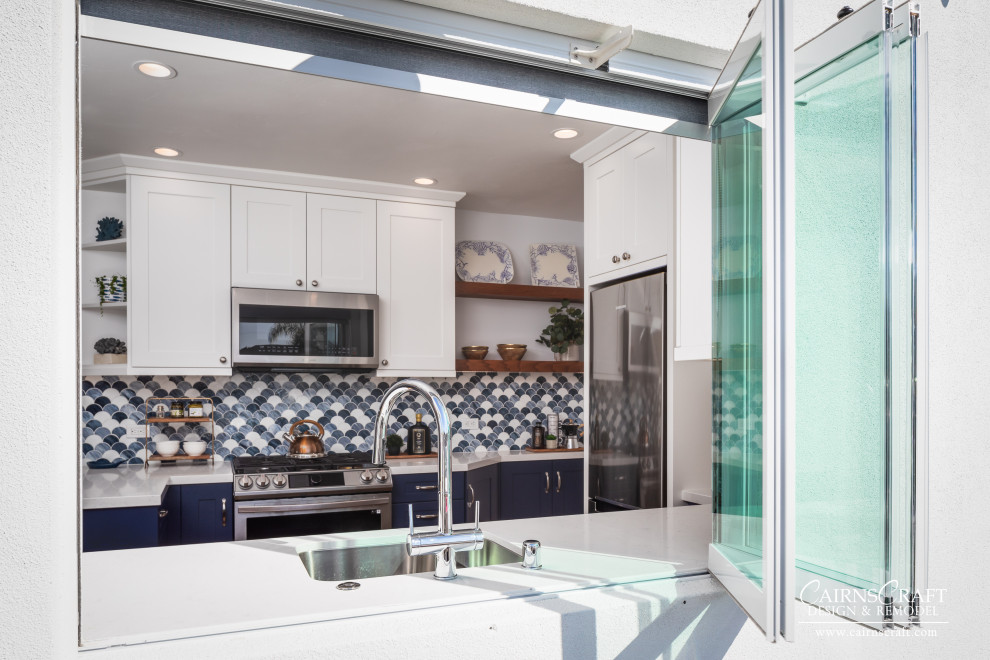 This is an example of a mid-sized beach style u-shaped eat-in kitchen in San Diego with a double-bowl sink, white cabinets, quartz benchtops, blue splashback, stainless steel appliances, medium hardwood floors, a peninsula, brown floor, white benchtop, shaker cabinets and glass sheet splashback.